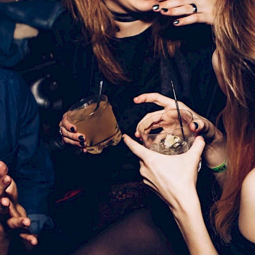 People are enjoying drinks at a social gathering or party, laughing and interacting with each other.