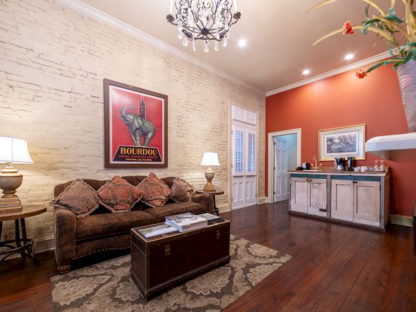 A cozy living room with a sofa, lamps, a vintage poster, a chest coffee table, and a sideboard against a warm-toned wall.