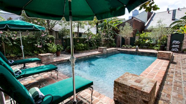 A swimming pool with green lounge chairs and umbrellas