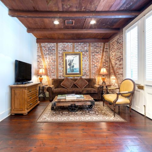 A cozy living room with a brick accent wall, sofa, coffee table, TV, rug, and decorative art piece, exuding a warm, inviting atmosphere.
