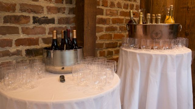 Two round tables with white tablecloths, metal buckets with wine bottles and wine glasses.